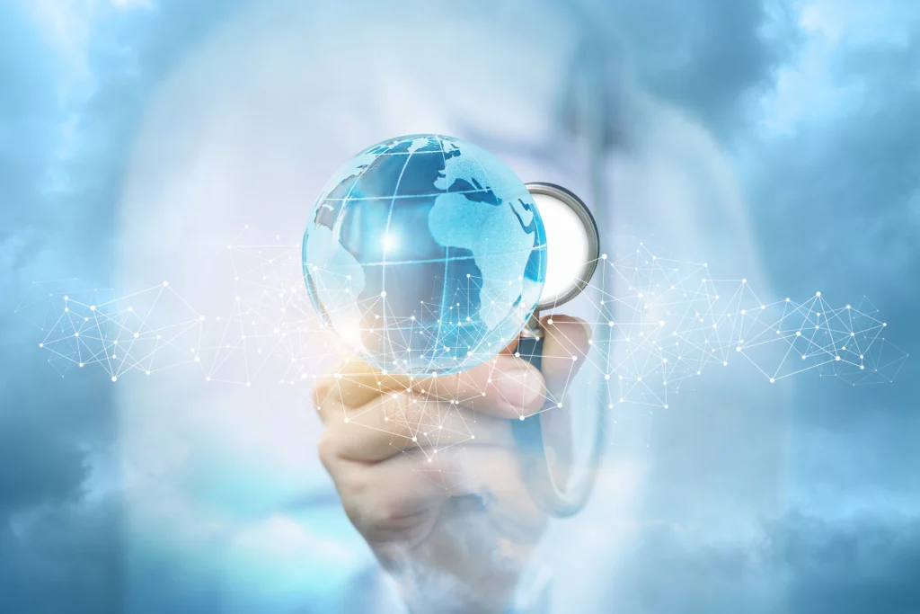 A hand holding a glowing globe with a stethoscope, symbolizing healthcare and global connectivity against a cloudy background.