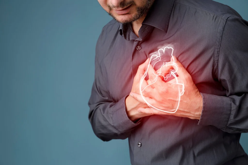 A man in a gray shirt holding his chest, with a glowing heart graphic overlay — representing early signs of heart disease.